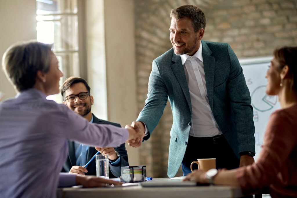 Business coworkers shaking hands during a meeting in the office. Focus is on a businessman.