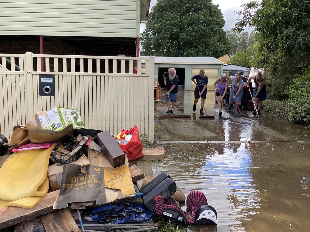 Volunteers sweeping driveway of flood damaged house