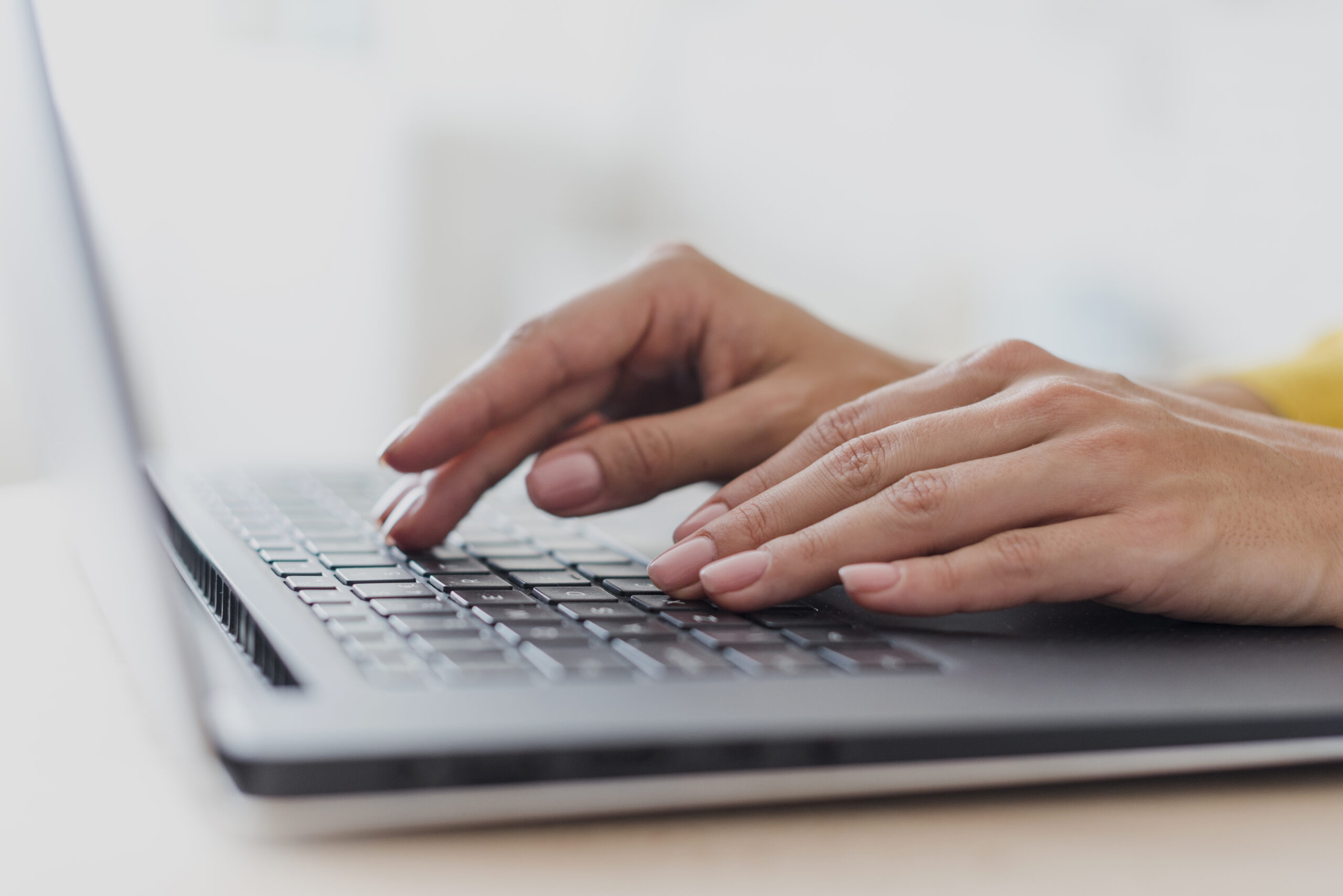 Close up of womans hands typing on laptop