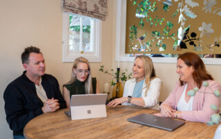 Cover Image for the Get Clear on Insurance Broker Fees blog by Clear Insurance female brokers sitting at table with clients discussing invoice broker fees