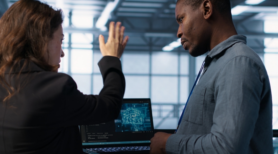 Two business professionals discussing AI risks while reviewing neural network graphics on a laptop Clear Insurance