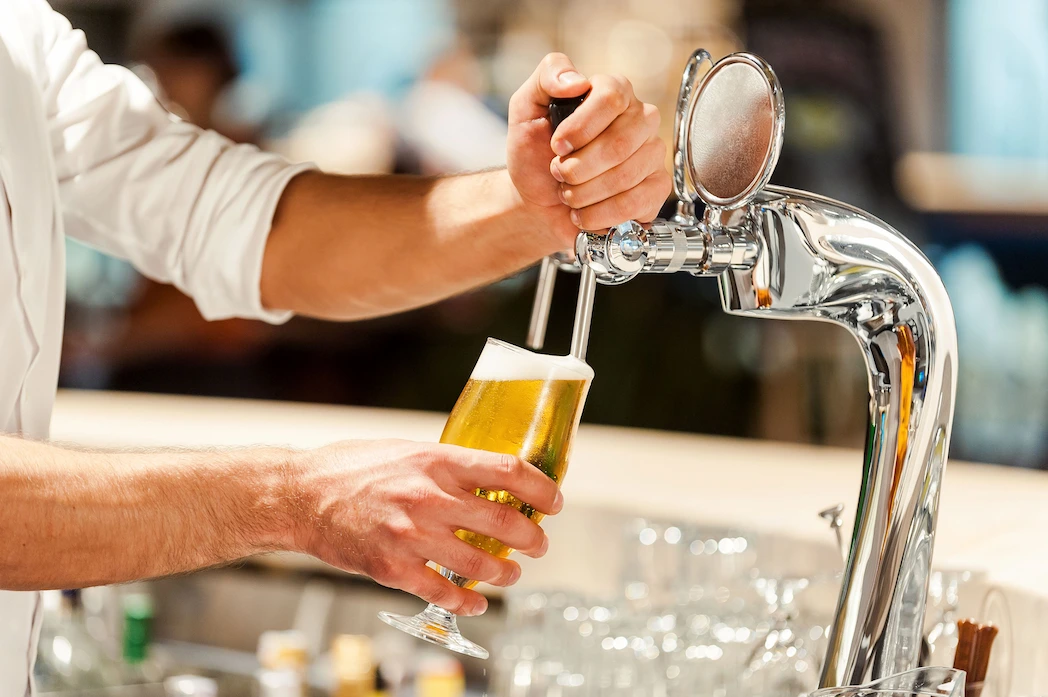Staff member pouring a drink from a beer tap.